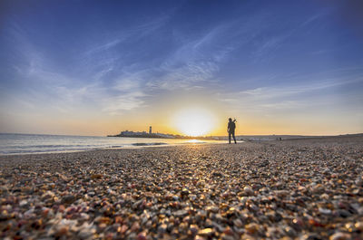 Full length of man standing by sea against sky during sunset