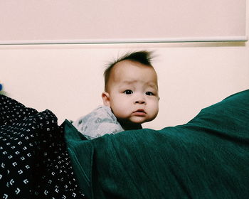 Portrait of cute baby boy on bed at home