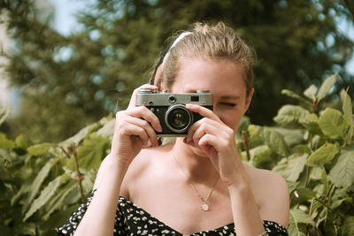 Young woman photographing against trees