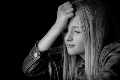 Portrait of a young woman against black background