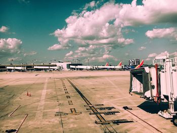 Passenger boarding bridge at airport runway against sky