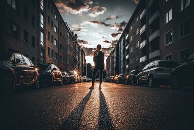 Rear view of woman standing on road in city against sky