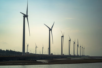 Windmills on field against sky during sunset