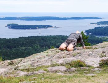 Woman bending body at beach against sky