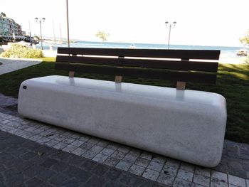 View of bench by swimming pool against sky