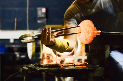 Midsection of worker making glass in workshop
