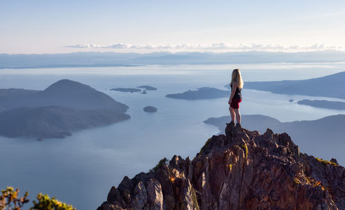 Man standing on rock against sky