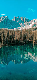 Scenic view of lake by snowcapped mountains against blue sky