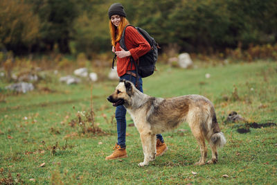 Full length of woman with dog standing on field