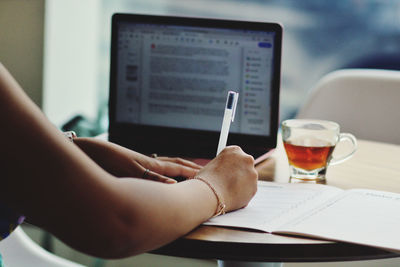 Midsection of man using laptop on table