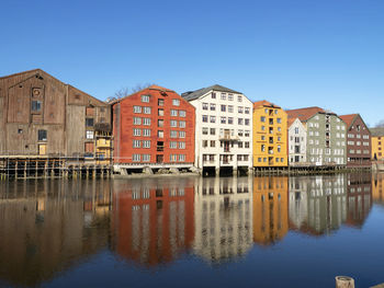 Colourful traditional old houses reflected in the river nidelva in trondheim, norway