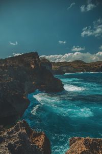 Scenic view of sea by mountains against sky