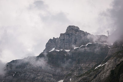 Low angle view of rock formation against sky during foggy weather