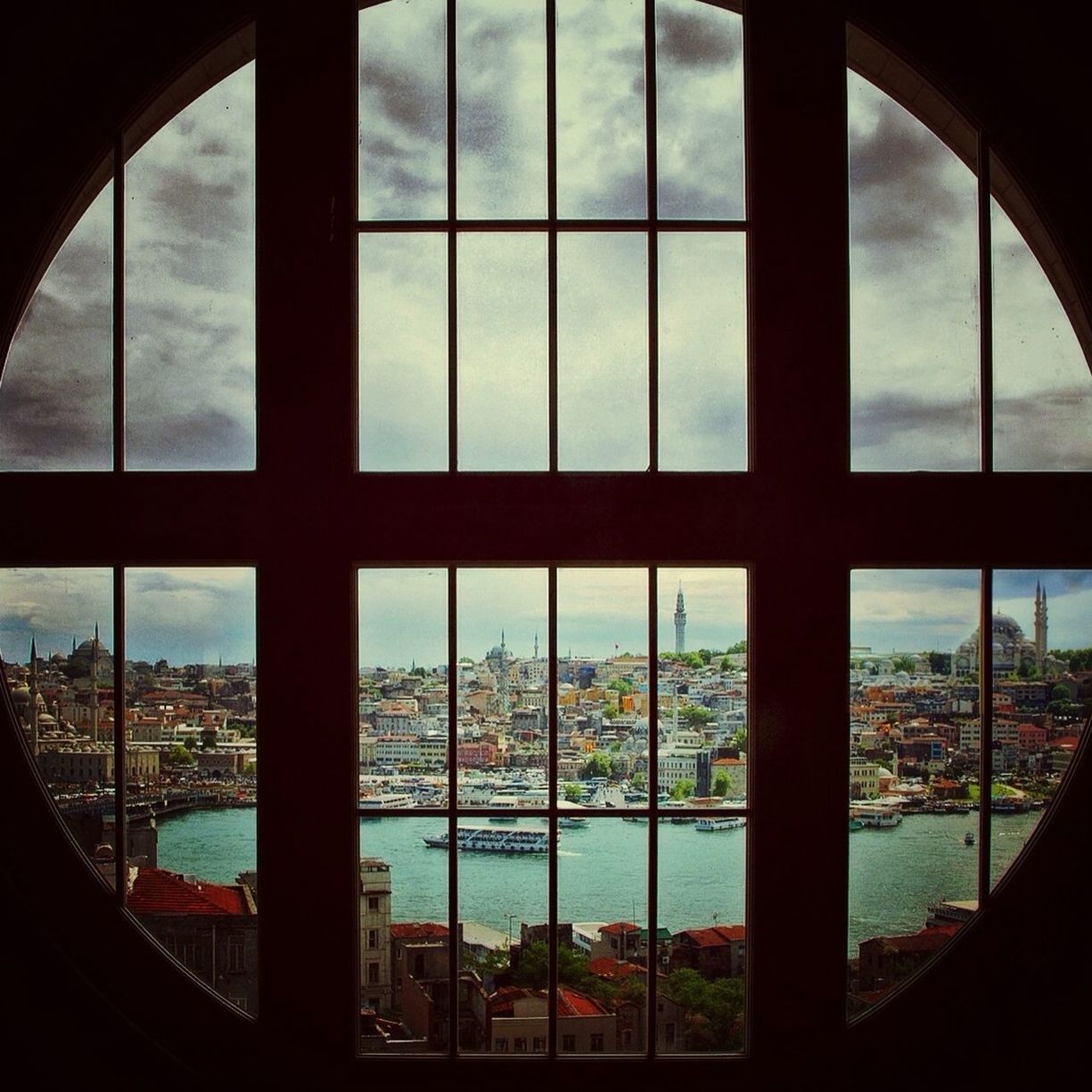 indoors, window, architecture, glass - material, transparent, built structure, sky, cloud - sky, day, city, glass, cityscape, building exterior, looking through window, tree, cloud, no people, pattern, arch, sunlight