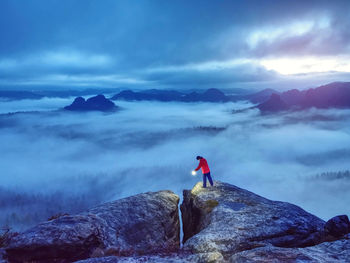 Beautiful lost woman hold in hands bright shining lamp on mountain summit. lighting into darkness