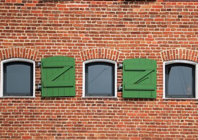 Full frame shot of brick wall with windows and green shutters