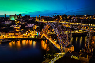 Illuminated bridge over river against sky at night