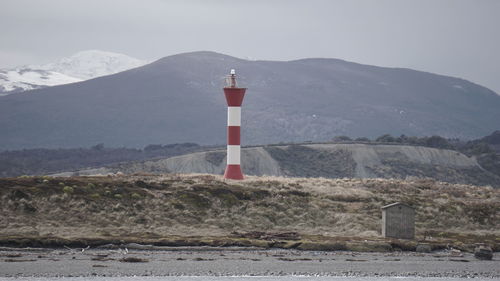 Lighthouse against mountain and sky