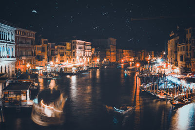 Illuminated buildings by canal in city at night