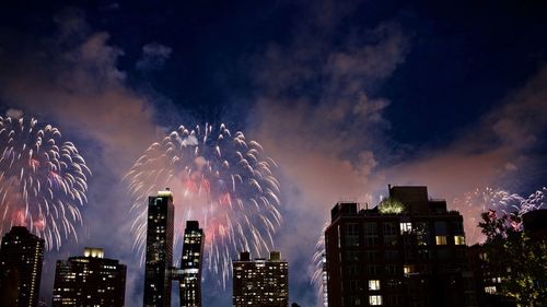 Low angle view of firework display over buildings at night