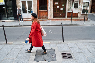 Full length of woman walking on footpath in city