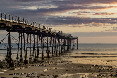 Pier over sea against sky during sunset