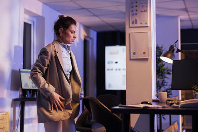 Side view of businesswoman using laptop while standing in office