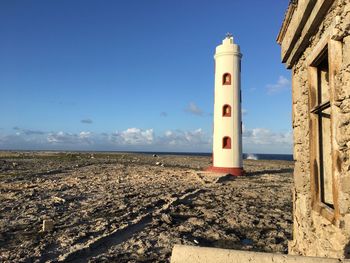 Lighthouse by sea against clear sky