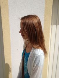 Side view of a young woman standing against wall