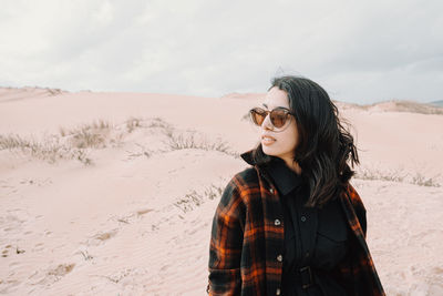 Portrait of young woman standing on sand at desert