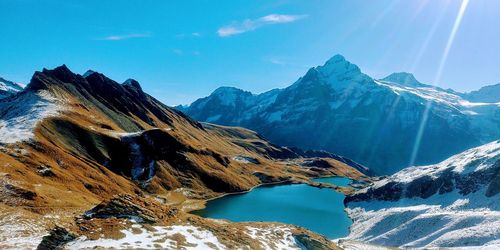 Scenic view of snowcapped mountains against blue sky