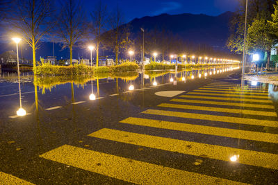 Illuminated street lights against sky at night