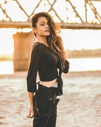 Side view portrait of young woman standing at beach during sunset