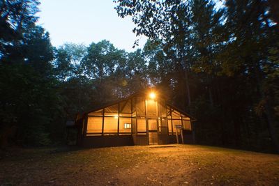 Illuminated built structure in forest against sky