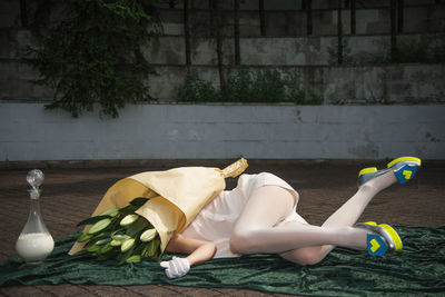 Low section of woman with face covered by flowers lying down