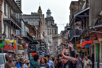 Crowd amidst buildings against sky in city