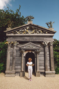 Full length of woman standing against wooden historic building