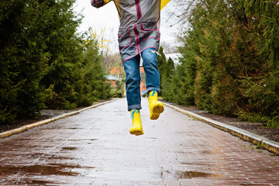 Jumping in puddle. female legs in yellow rubber boots jumping on the puddle. carefree young woman