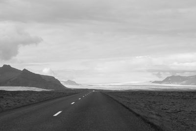 Empty road amidst landscape against sky