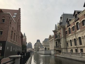 Canal amidst buildings in town against sky