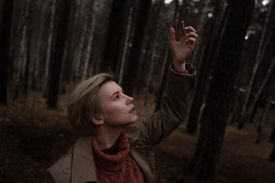 Girl looking up while standing on tree trunk