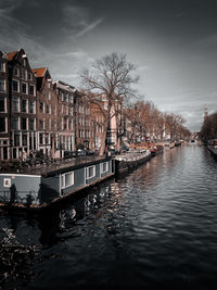 Buildings by river against sky