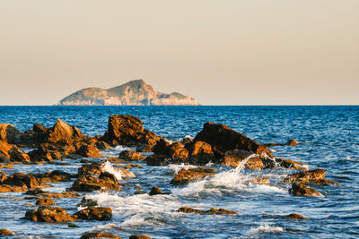 Scenic view of rocks in sea against clear sky