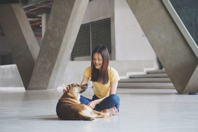 Young woman with dog sitting on floor