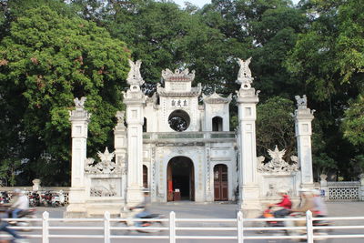 Blurred motion of people on motor scooter against temple