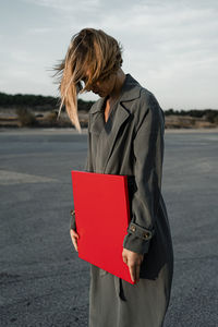 Woman with umbrella standing on road