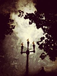 Low angle view of tree against cloudy sky