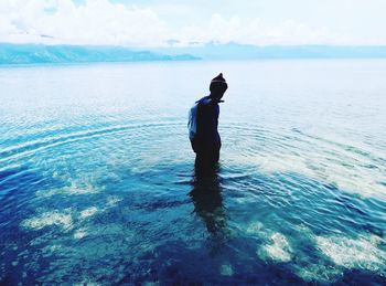 Man standing in swimming pool against sea