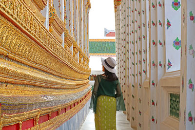 Female visitor admiring the incredible details of wat arun buddhist temple, bangkok, thailand