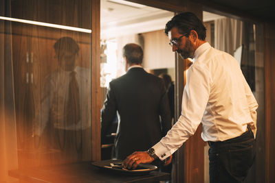 High angle view of mature legal professional keeping mobile phone on tray outside board room